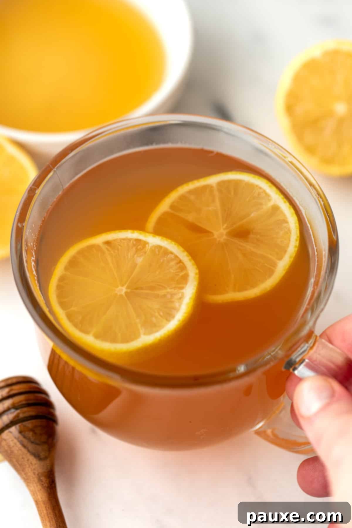 A glass mug filled with tea and garnished with fresh lemon slices.