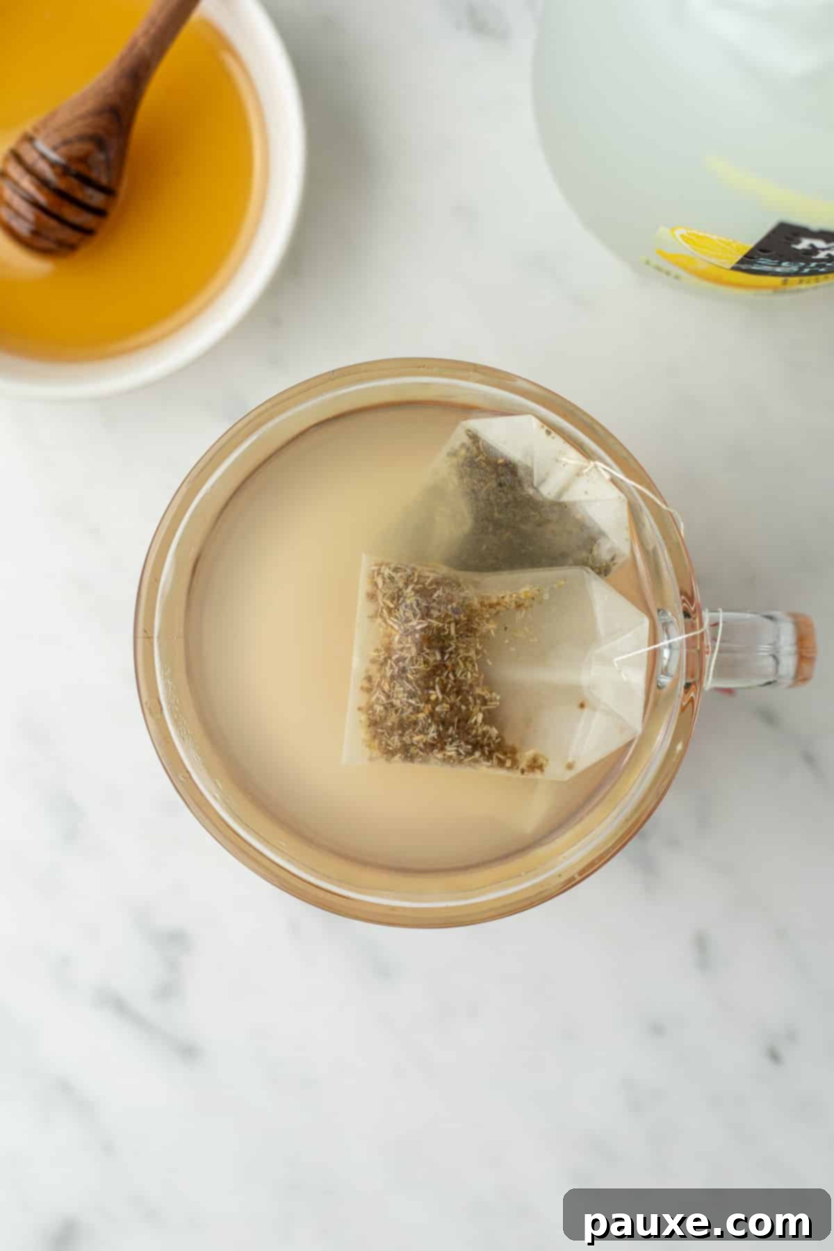 3 tea bags in a glass mug of warm liquid.