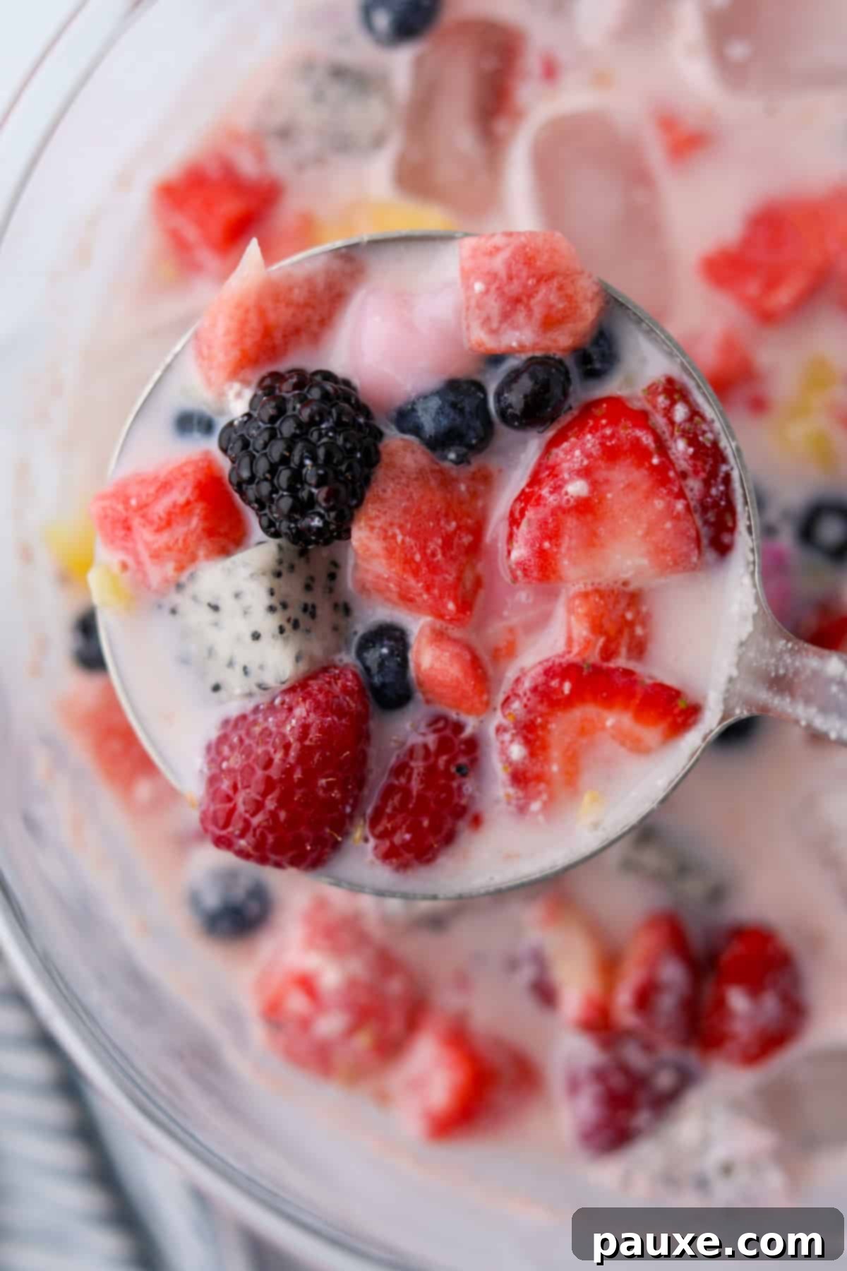 A ladle filled with fruit and milk.