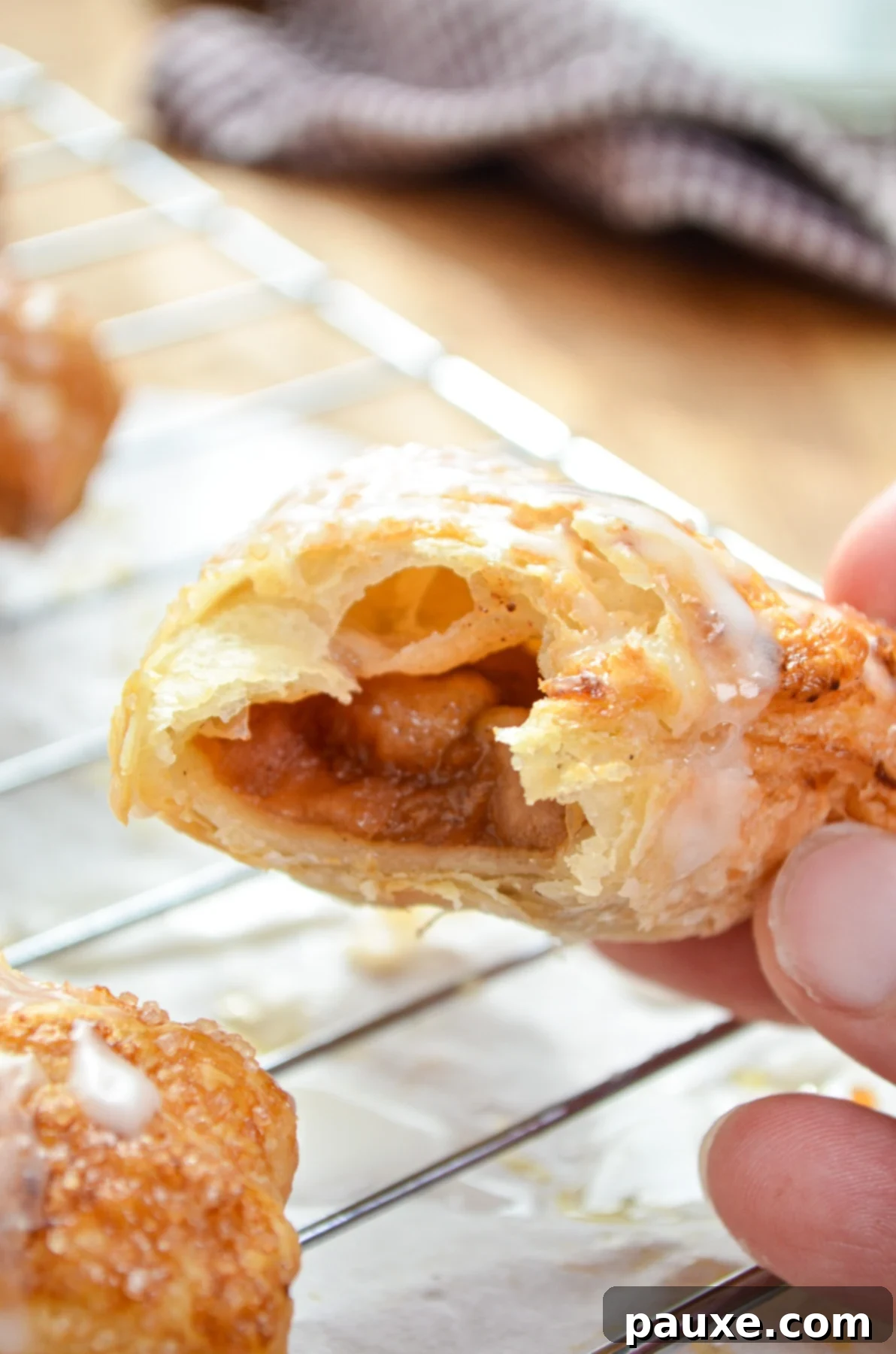 Golden Air Fried Apple Delights 10 A golden-brown apple turnover, with a bite taken out, resting on a wire rack after being baked.