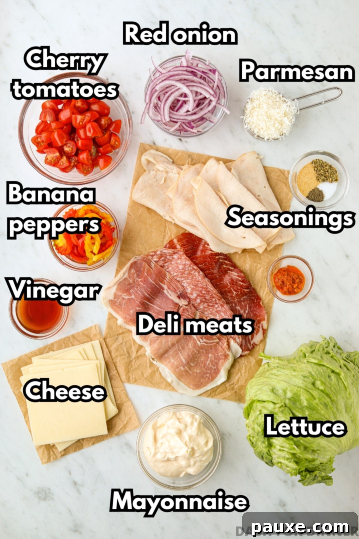 Hero Salad Bowl 3 The vibrant ingredients needed to make grinder salad, including a variety of deli meats, cheese slices, fresh lettuce, red onion, cherry tomatoes, banana peppers, mayonnaise, and seasonings.