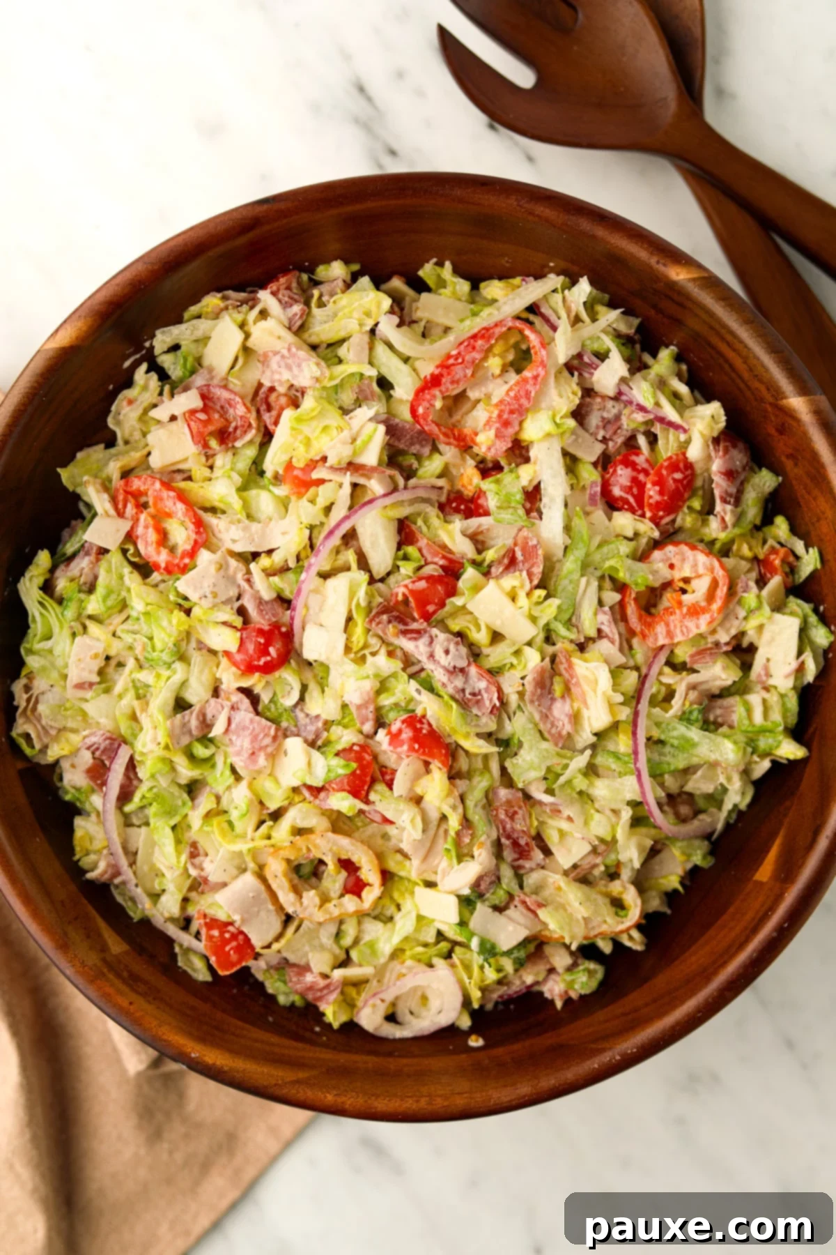 Hero Salad Bowl 7 A rustic wooden bowl brimming with a perfectly creamy and vibrant chopped Grinder Salad, ready to be enjoyed.