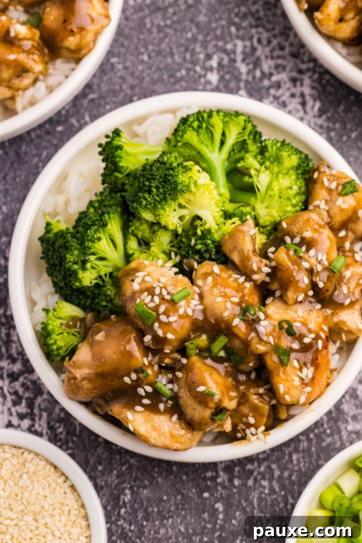 Sticky Honey Ginger Chicken 7 A vibrant bowl featuring cooked honey ginger chicken nestled on a bed of rice, accompanied by bright green steamed broccoli.