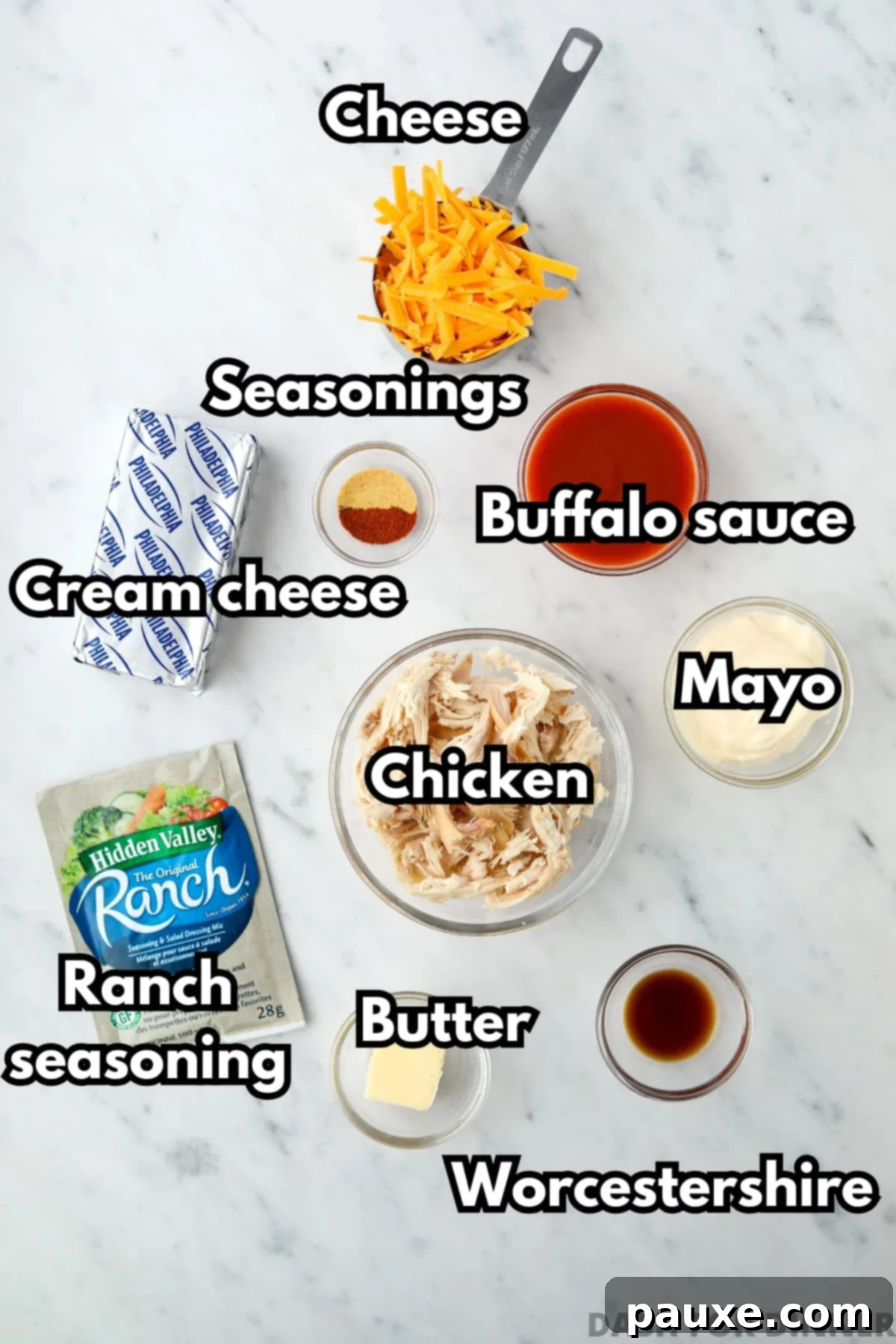 Irresistible Buffalo Chicken Dip 3 A flat lay of the ingredients required for making buffalo chicken dip, including softened cream cheese, cooked shredded chicken, a bottle of buffalo sauce, cheddar cheese, and other seasonings.