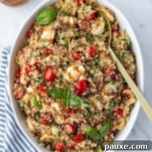 Vibrant Quinoa Caprese 8 A large bowl filled with quinoa salad, garnished with fresh basil, sliced mini mozzarella, and balsamic glaze.