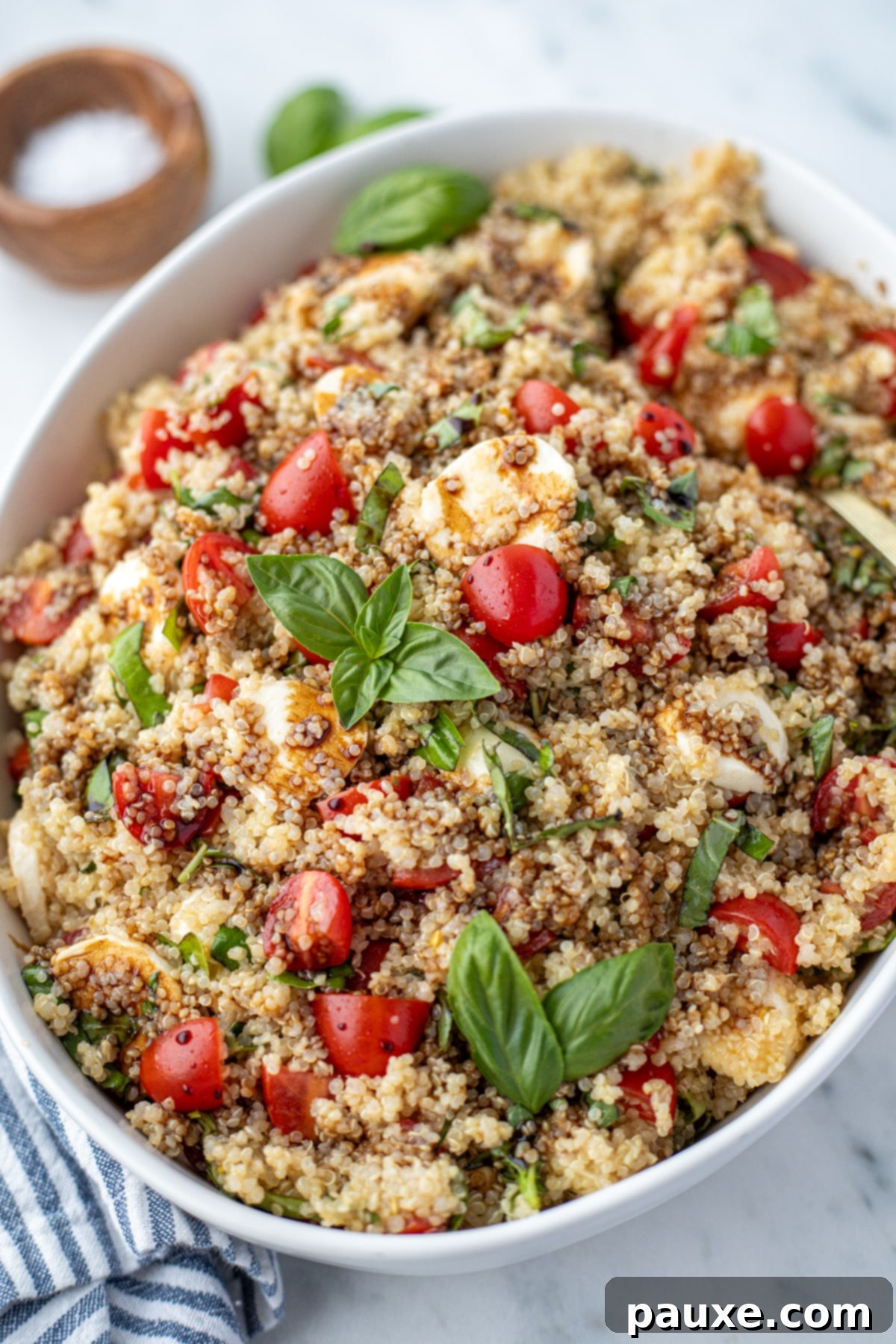 Vibrant Quinoa Caprese 6 A large bowl of quinoa salad topped with fresh basil and tomatoes.