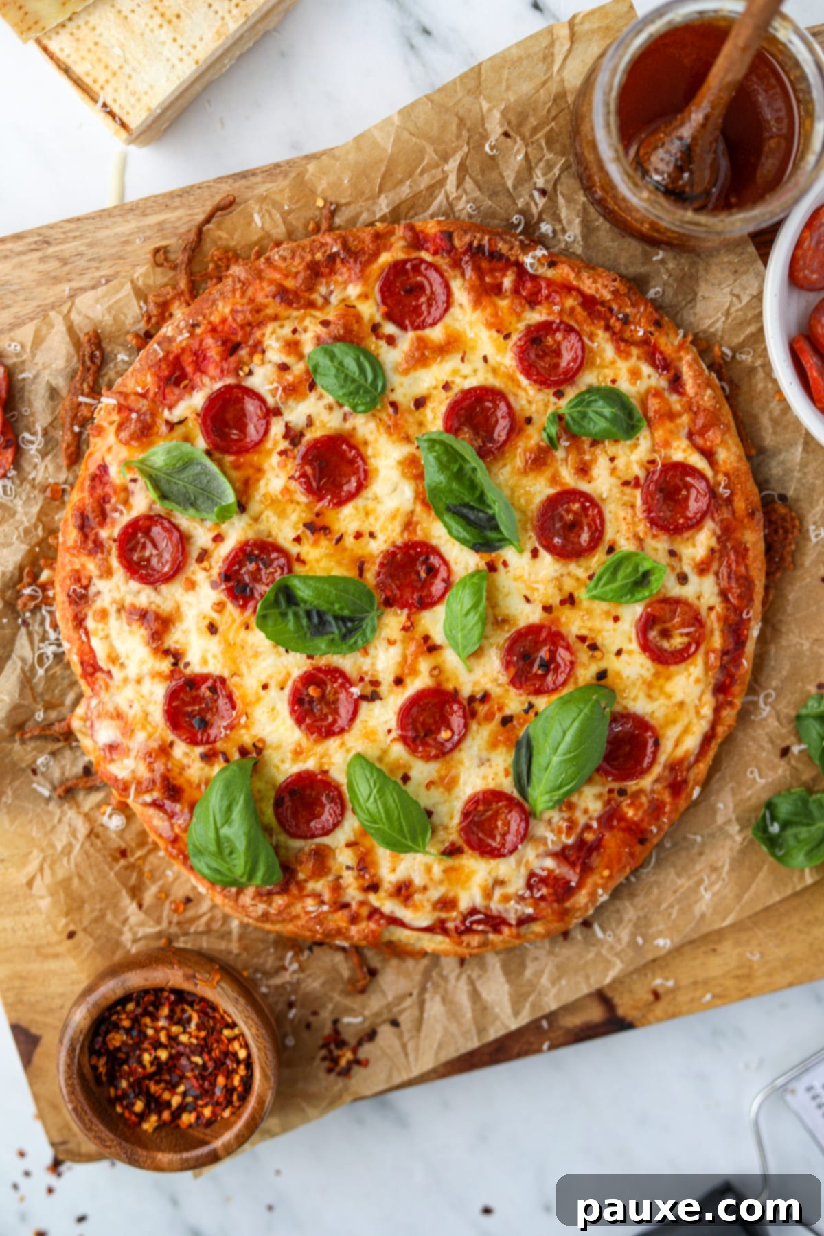 Wholesome Yogurt Pizza 6 Pizza on a sheet of parchment paper, beautifully topped with pepperoni, fresh basil, and a sprinkle of crushed red pepper.