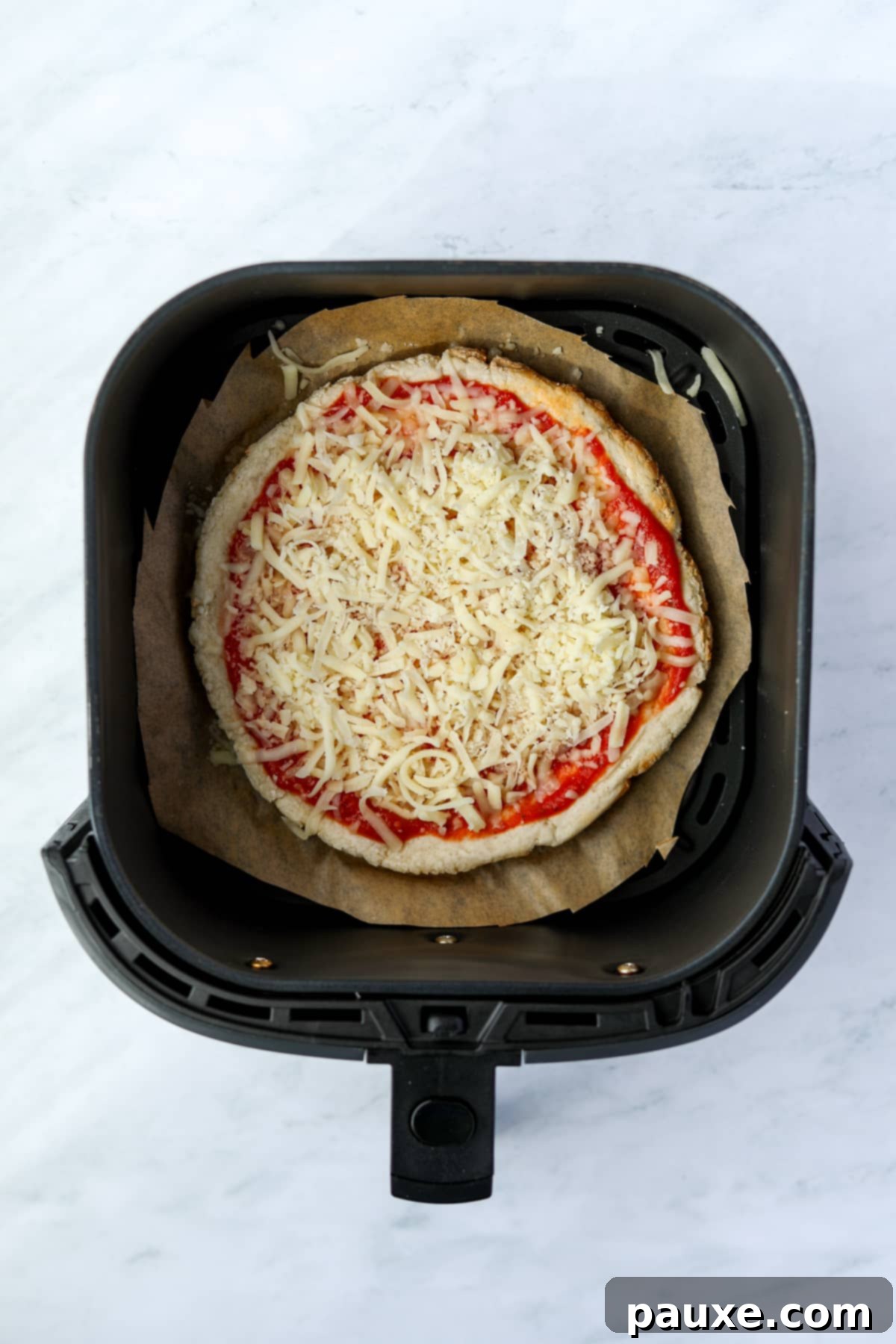 Wholesome Yogurt Pizza 8 An air fryer with an uncooked mini pizza inside, ready for a quick bake.