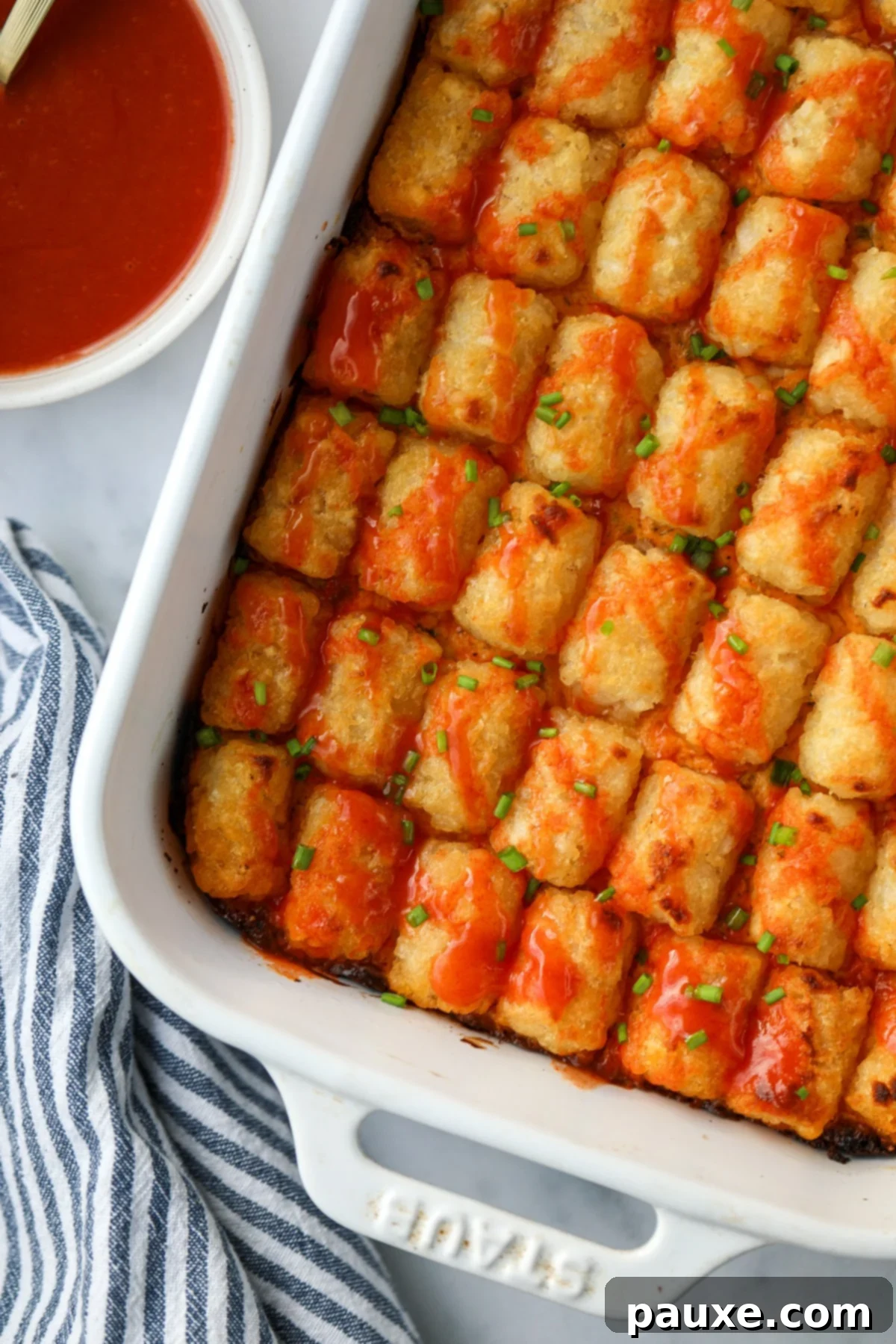 Fiery Buffalo Tot Bake 2 A baking dish filled with tater tot casserole topped with a drizzle of buffalo sauce.