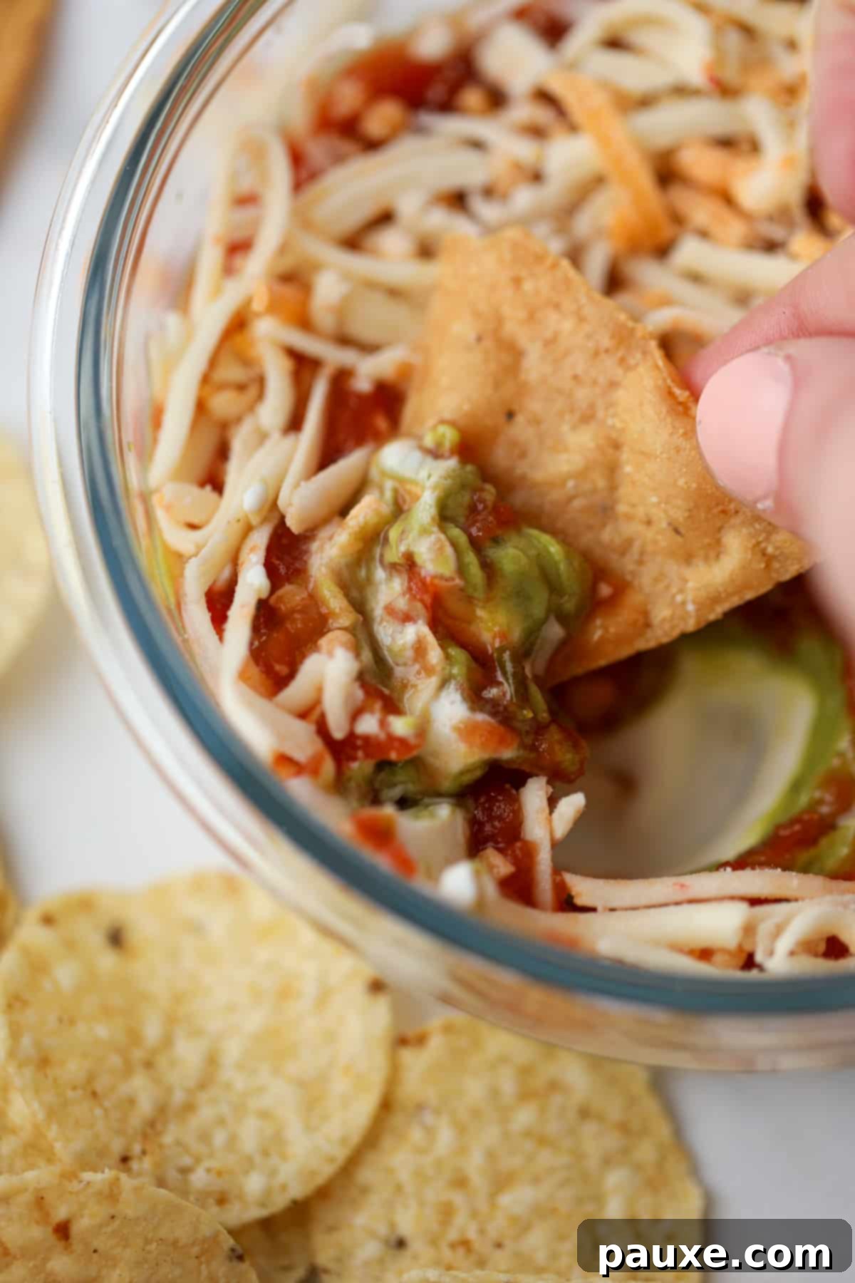 Power-Packed Greek Yogurt Dip 6 A tortilla chip being dipped into a small bowl of layered dip.