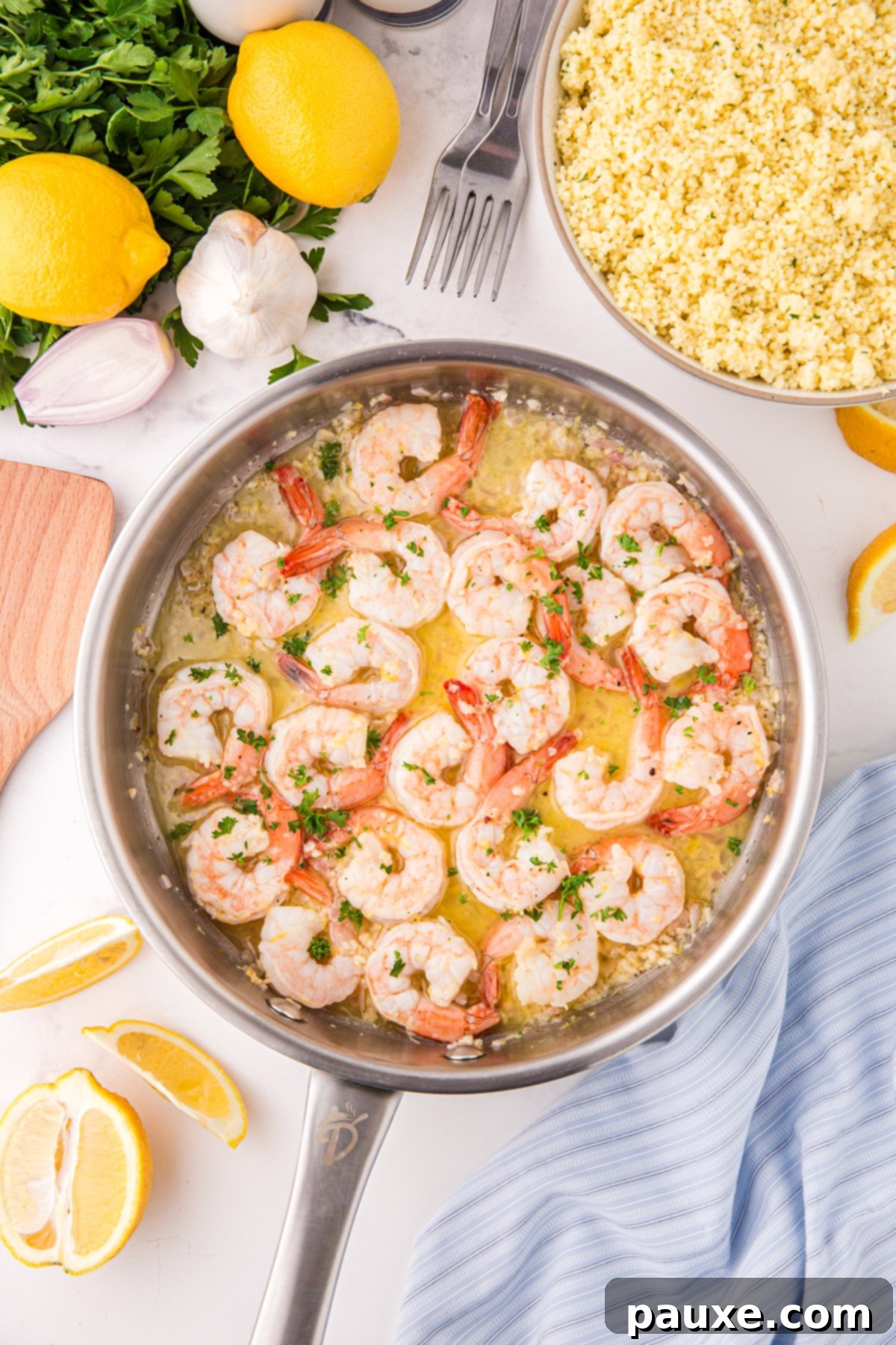 Zesty Lemon-Garlic Butter Shrimp 5 A gleaming stainless steel skillet filled with perfectly cooked lemon garlic butter shrimp, garnished with fresh parsley and lemon wedges arranged artfully on the side.