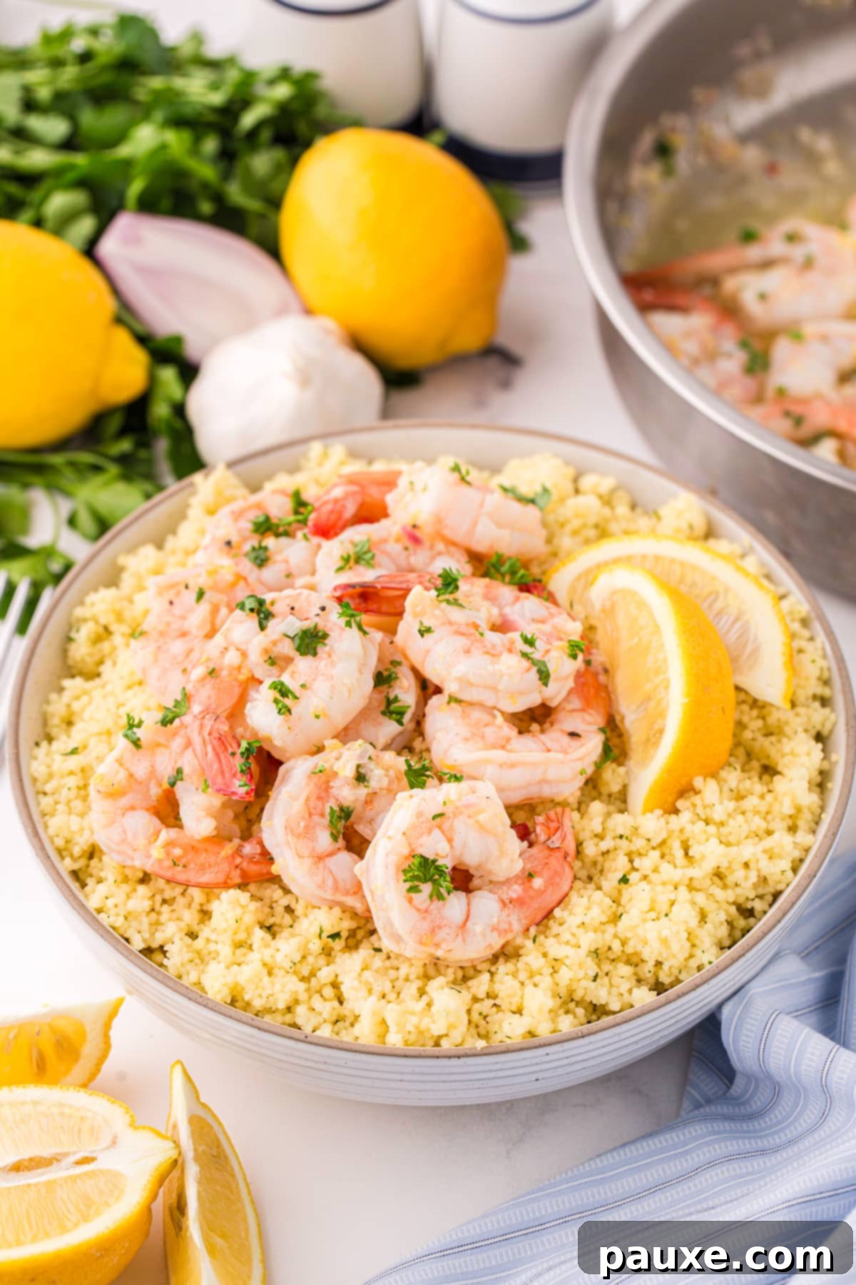 Zesty Lemon-Garlic Butter Shrimp 6 Plump, cooked lemon garlic butter shrimp elegantly arranged over a bowl of fluffy quinoa, garnished with fresh lemon wedges.