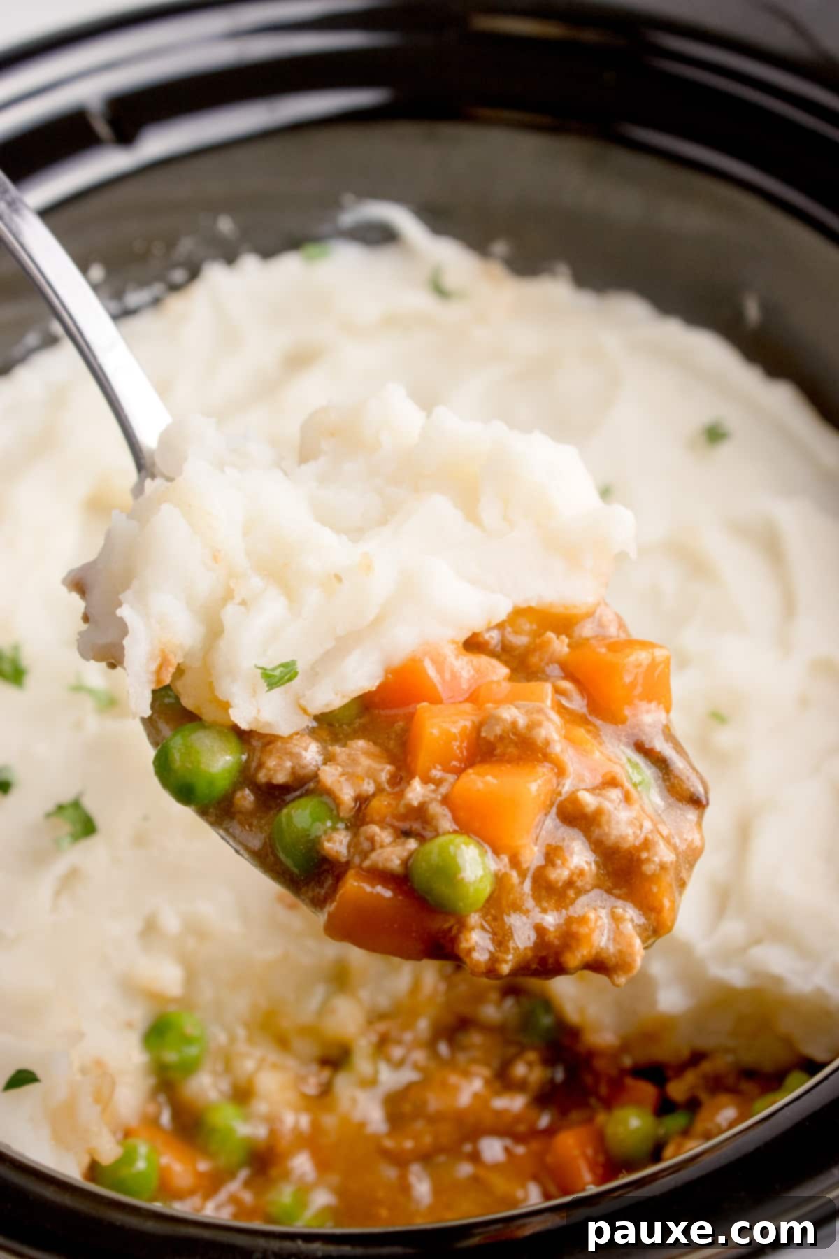Set-It-And-Forget-It Shepherd's Pie 6 Taking a large scoop of shepherd's pie from a slow cooker.