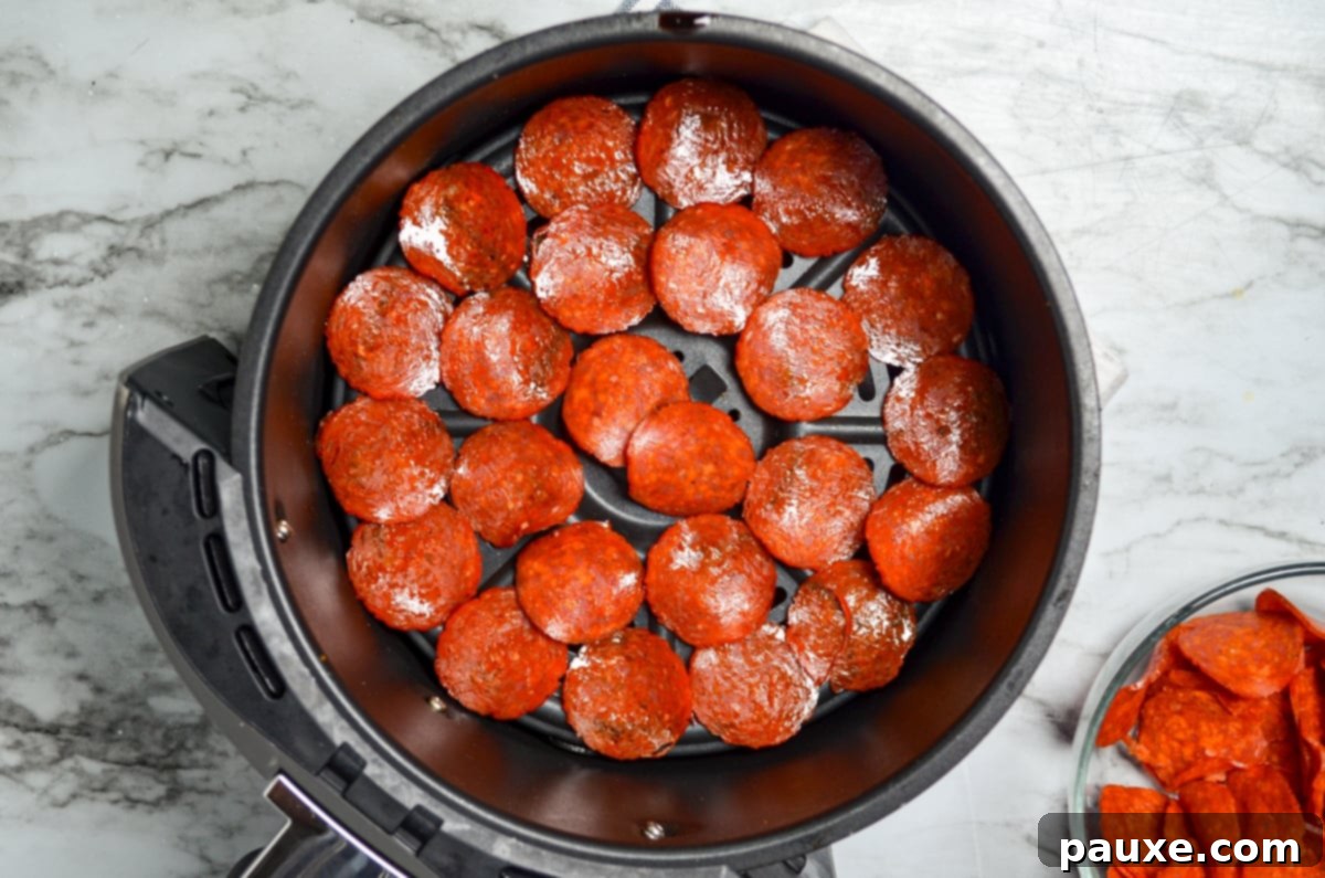 Air Fried Crispy Pepperoni 6 Pepperoni layered in the basket of an air fryer.