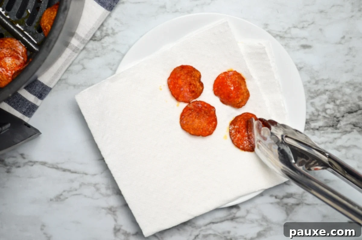 Air Fried Crispy Pepperoni 8 Air fryer pepperoni chips being drained on a double layer of paper towels.