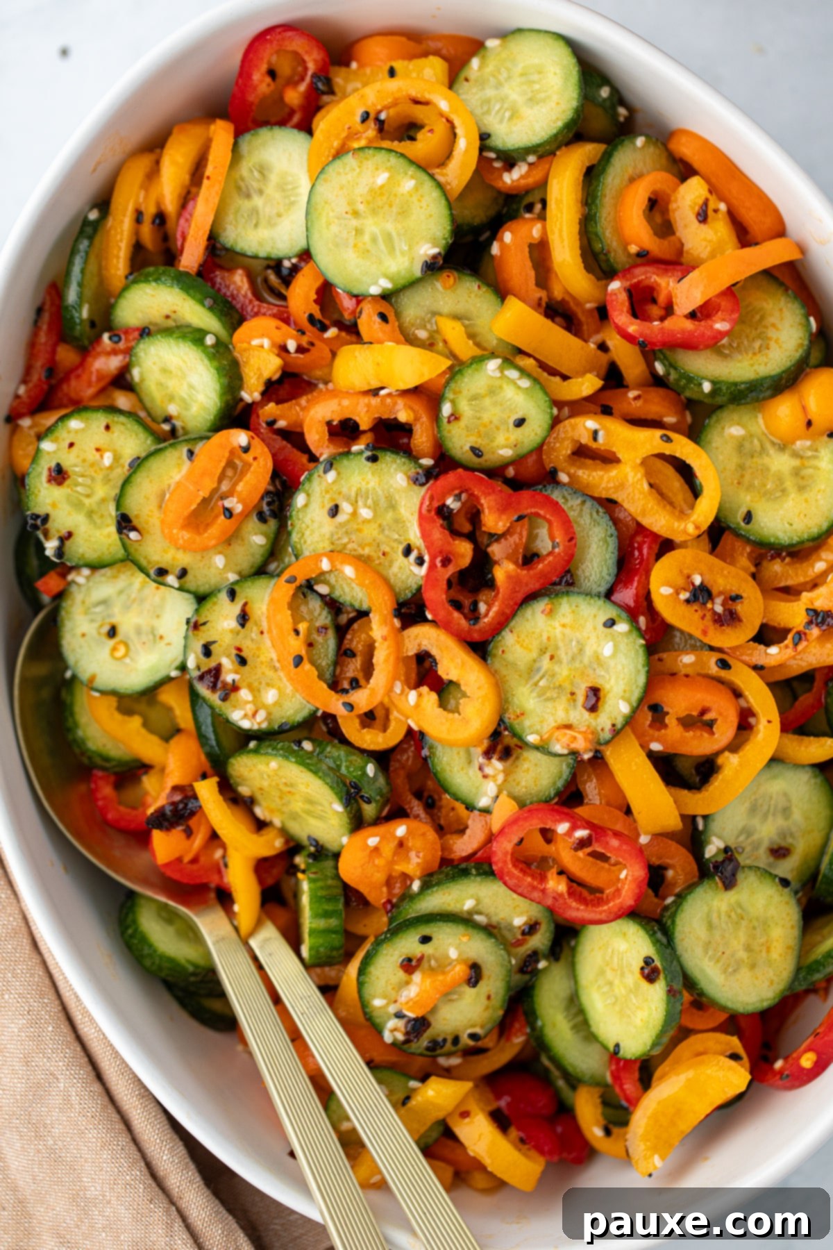 A bowl filled with cucumber and mini sliced bell pepper, topped with sesame seeds.