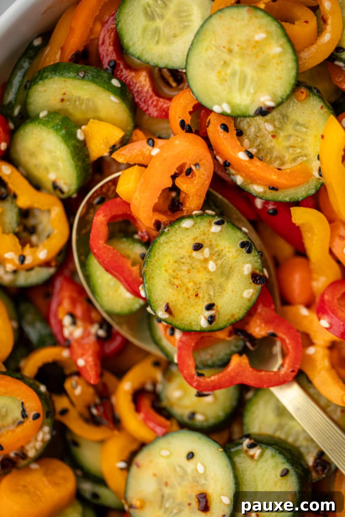 A spoon serving up a portion of cucumber and bell pepper salad.