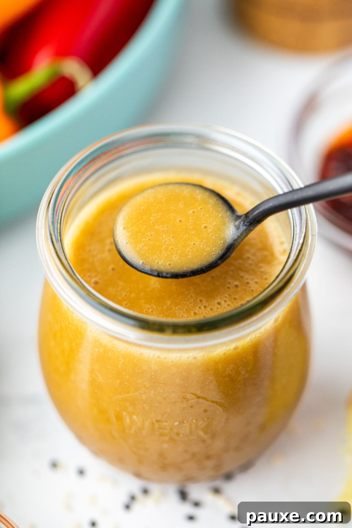 A spoon taking a small amount of homemade vinaigrette from a small jar.