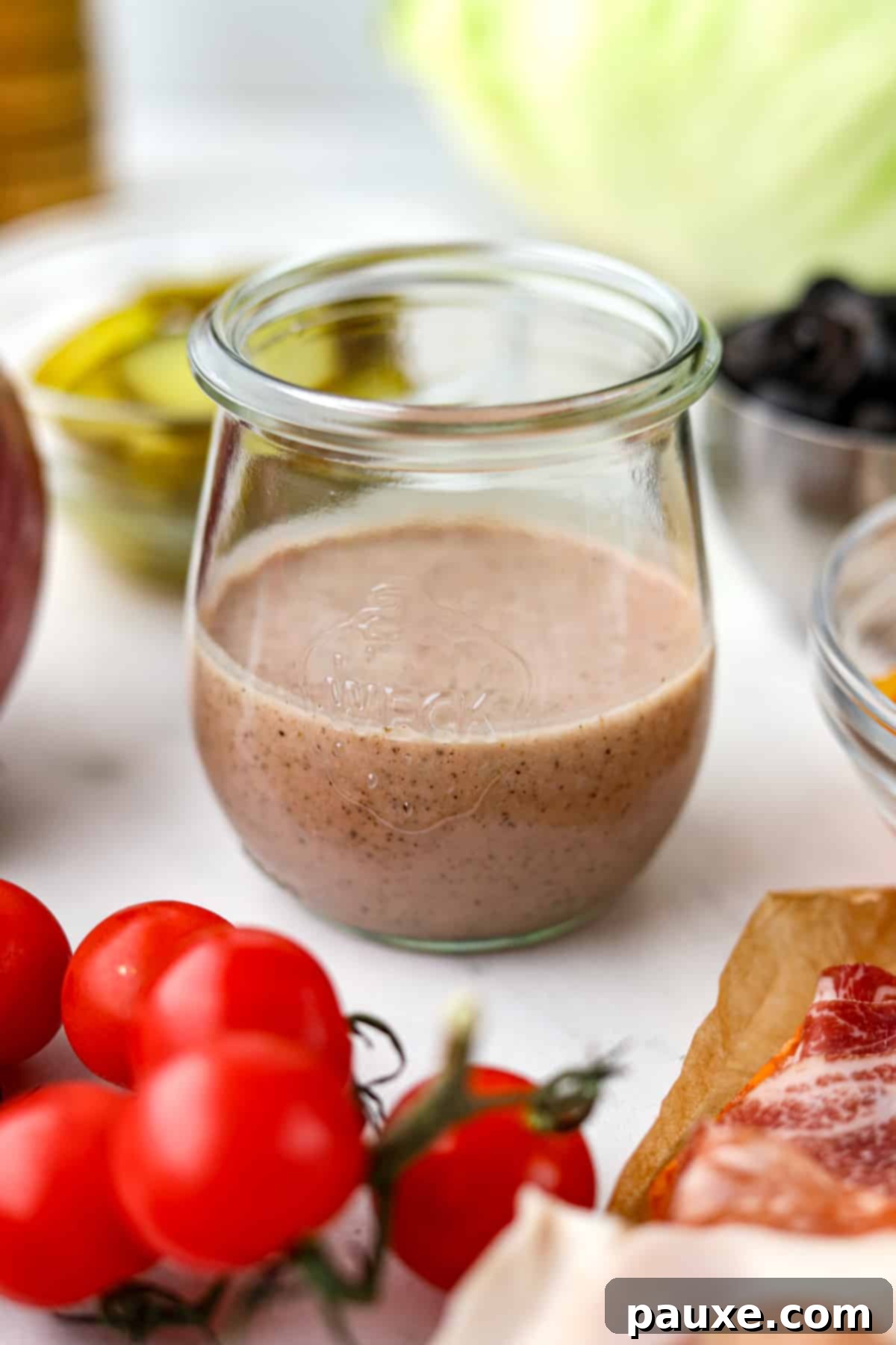 The Sub Secret 6 A small jar filled with Italian sub dressing, surrounded by cherry tomatoes, lettuce, and other fresh ingredients.