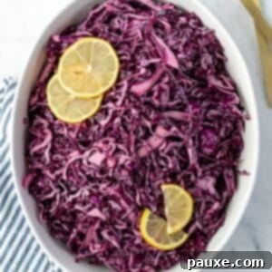 Fresh Israeli Cabbage Slaw 12 An oval bowl filled with vibrant red cabbage salad, garnished with fresh lemon slices.
