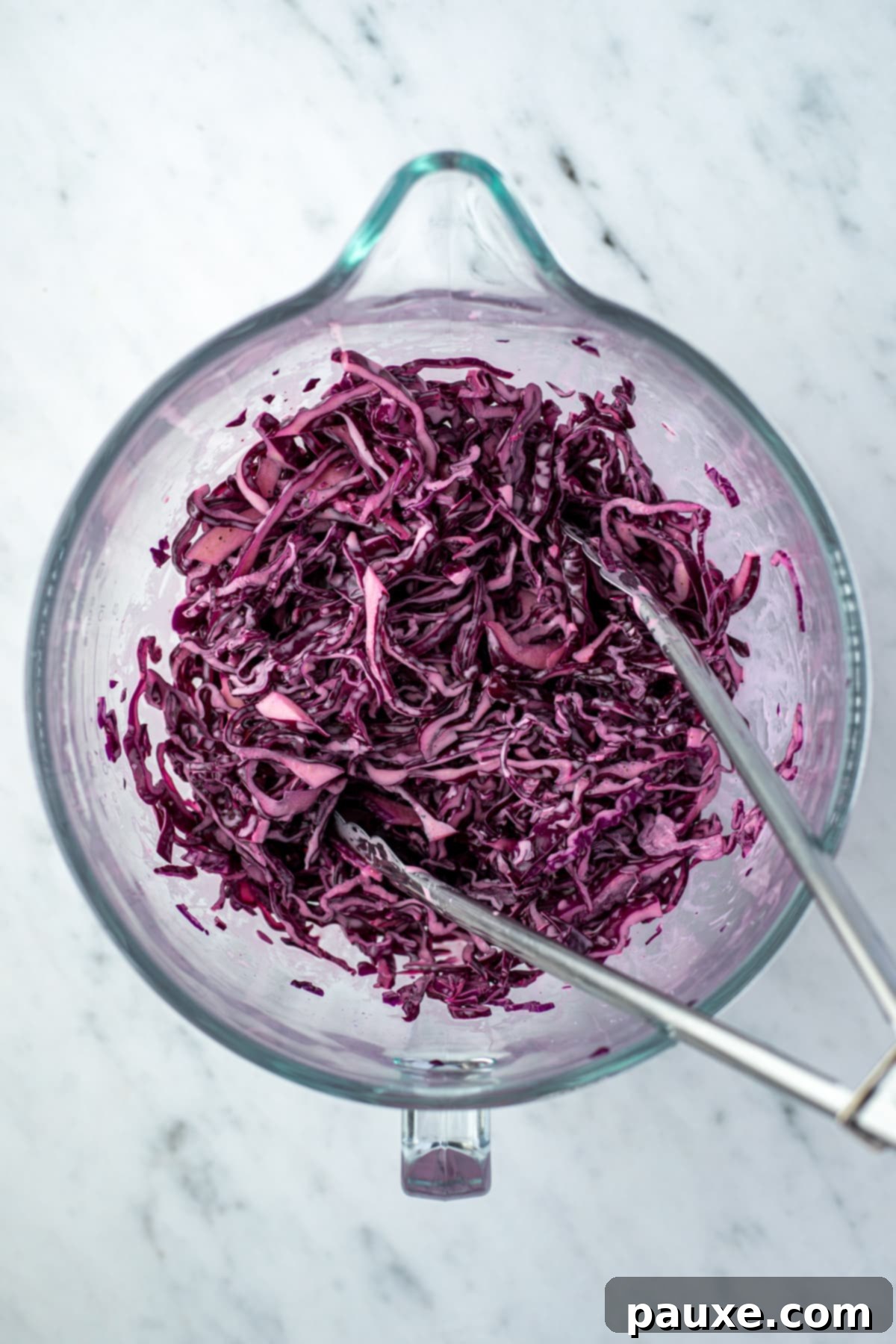 Fresh Israeli Cabbage Slaw 8 The creamy dressing being drizzled over the salted, shredded red cabbage in a large bowl, ready for tossing.