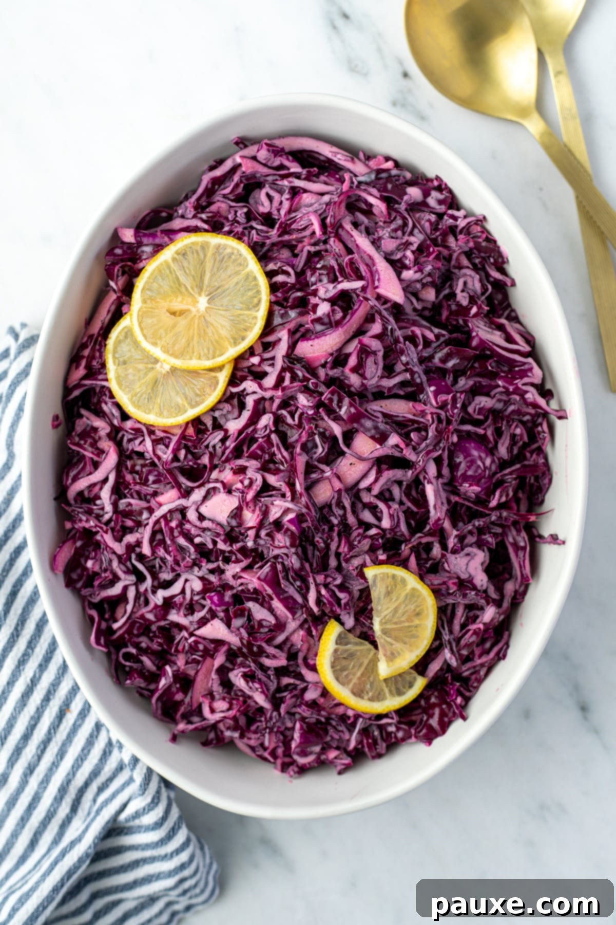 Fresh Israeli Cabbage Slaw 9 An oval serving bowl generously filled with bright red cabbage salad, elegantly topped with fresh lemon slices, ready to be presented.