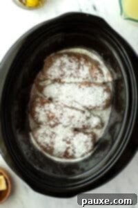 Mississippi Pot Roast Chicken 13 Sprinkling ranch seasoning on top of chicken breasts in a slow cooker.