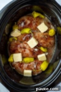 Mississippi Pot Roast Chicken 14 A slow cooker with chicken, seasoning, butter, and pepperoncini peppers.