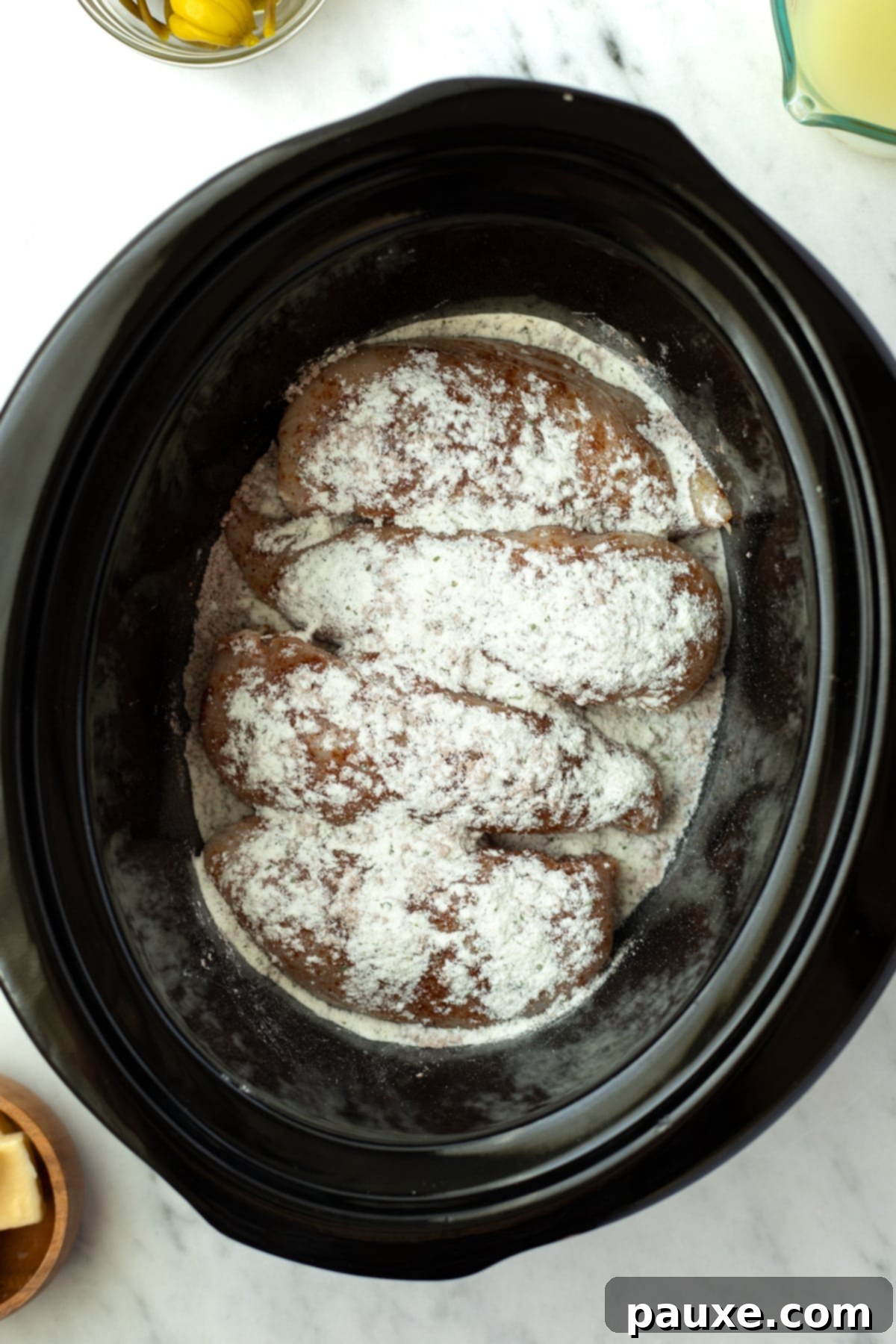 Mississippi Pot Roast Chicken 4 Sprinkling ranch seasoning generously on top of raw chicken breasts laid out in a slow cooker.