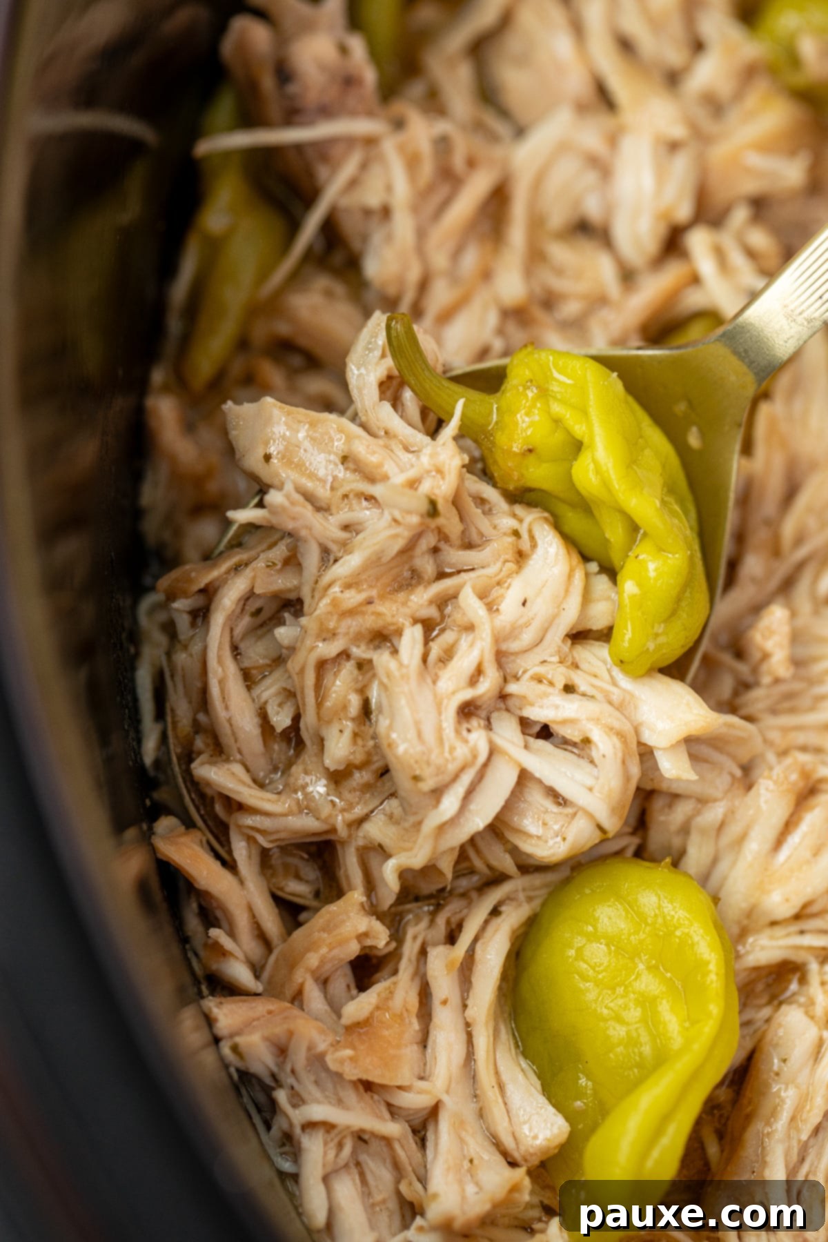 Mississippi Pot Roast Chicken 9 A spoon scooping a generous portion of flavorful shredded chicken from a slow cooker, emphasizing its readiness to serve.