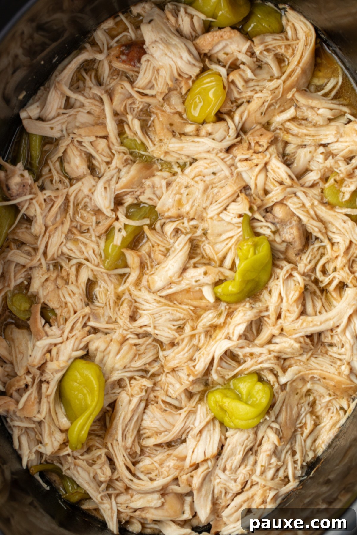 Mississippi Pot Roast Chicken 10 A crock pot filled with rich, shredded chicken, garnished with a few pepperoncini peppers on top.