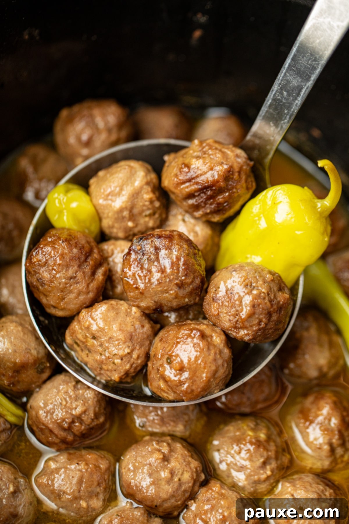 Dixie Glazed Meatballs 2 A ladle full of meatballs with pepperoncini peppers.