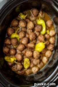 Dixie Glazed Meatballs 13 A slow cooker filled with cooked meatballs mixed with a thin sauce and pepperoncini peppers.