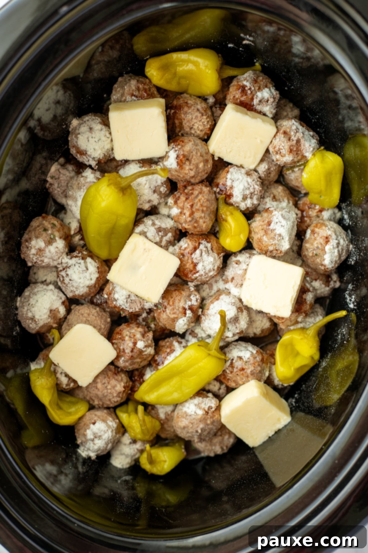 Dixie Glazed Meatballs 5 A slow cooker filled with meatballs, pepperoncini peppers, and butter.