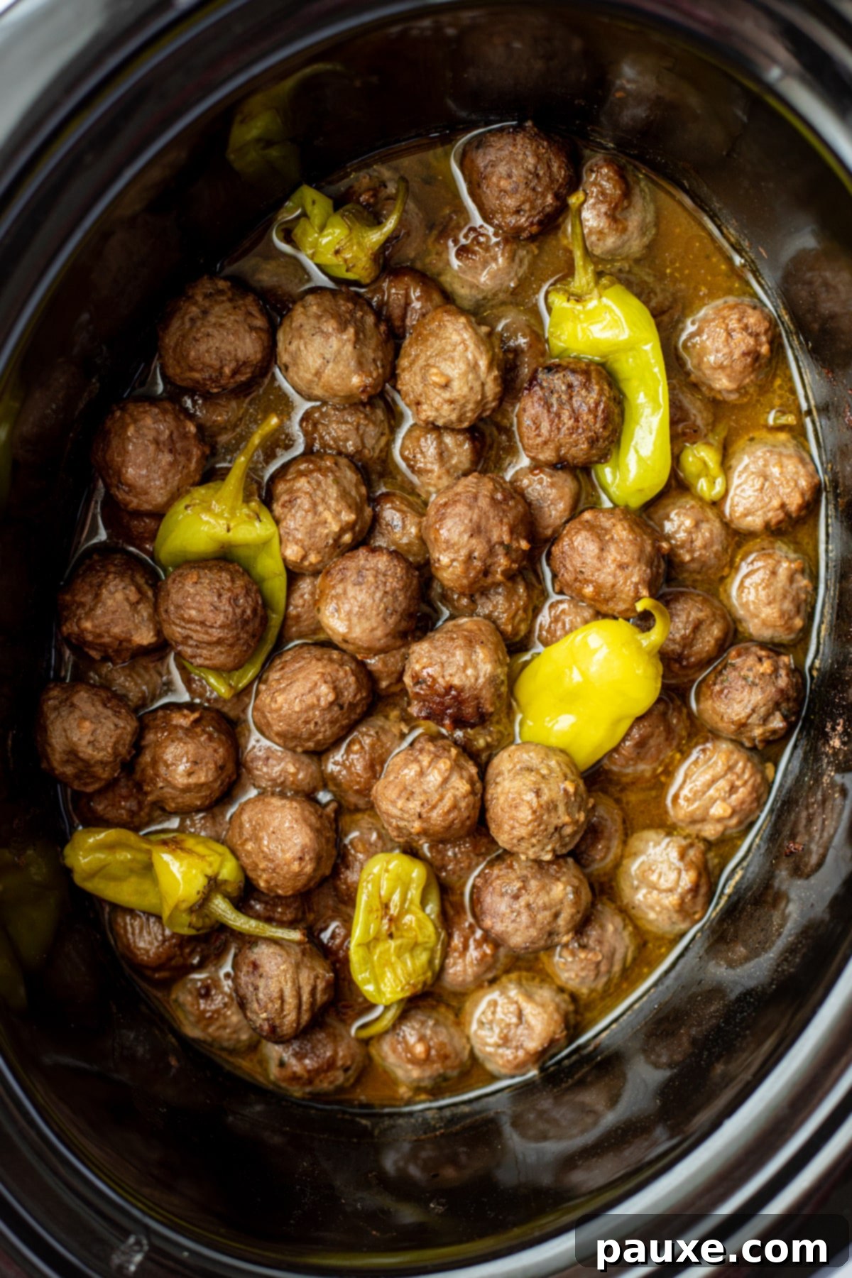 Dixie Glazed Meatballs 6 A slow cooker filled with cooked meatballs mixed with a thin sauce and pepperoncini peppers.