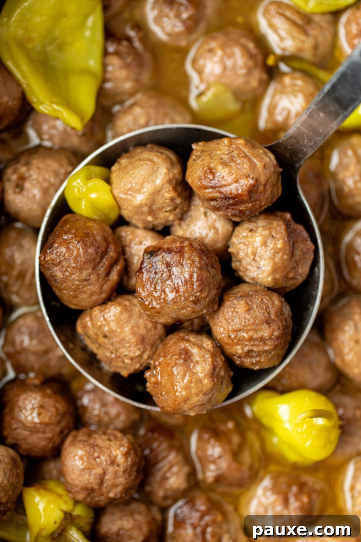 Dixie Glazed Meatballs 9 A ladle full of meatballs, with several scattered pepperoncini peppers around.