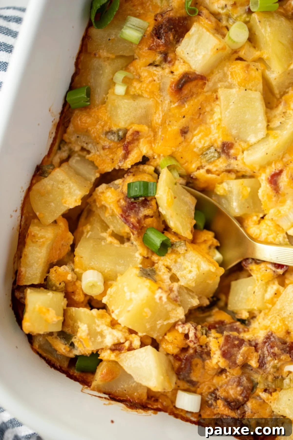 Deep South Midnight Spuds 2 A spoon scooping into a potato casserole with cheese and bacon.