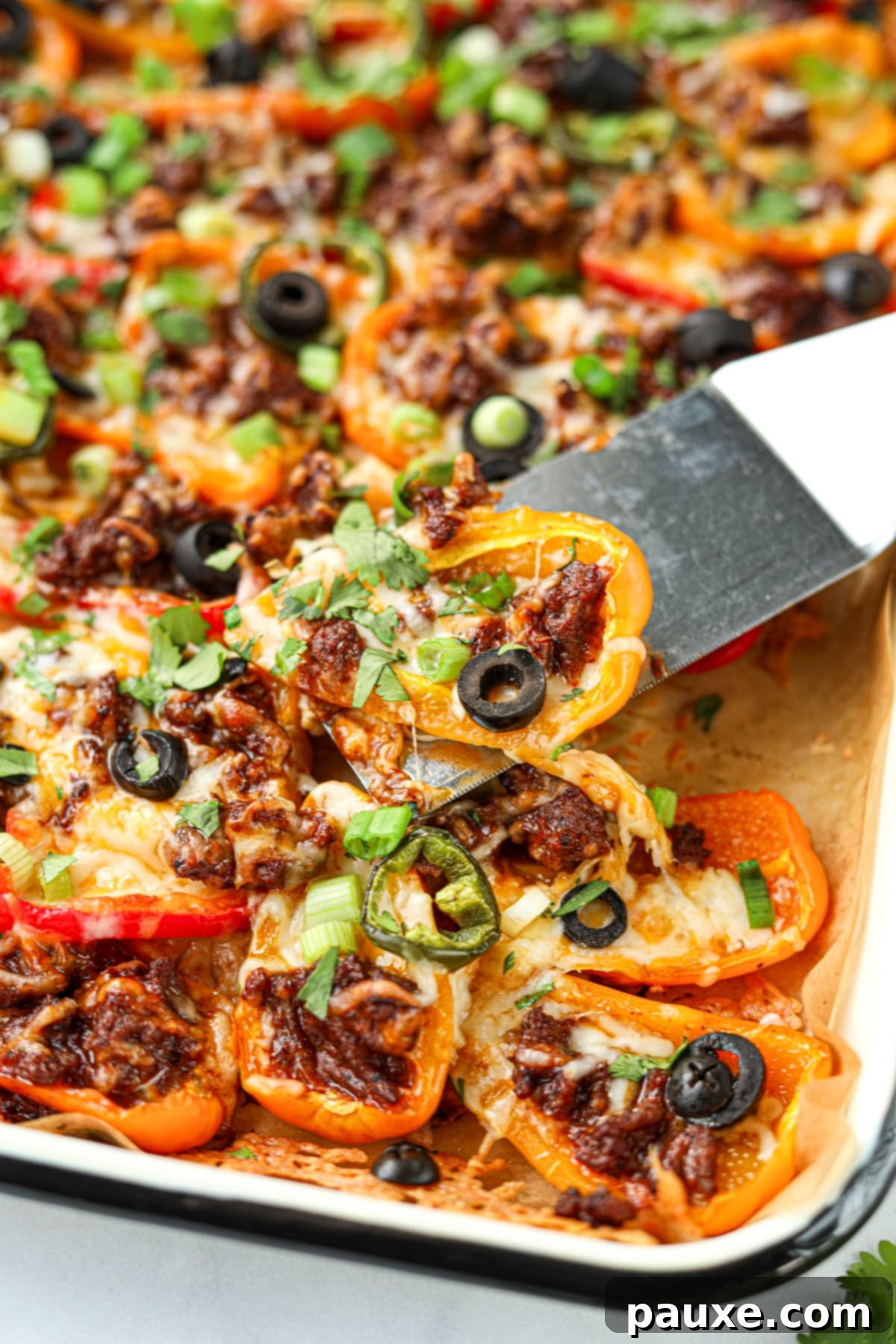 Bell Pepper Nacho Boats 5 A delicate shot of bell pepper nachos being lifted from a baking sheet with a small spatula, showcasing the perfect melt of cheese and delicious toppings.