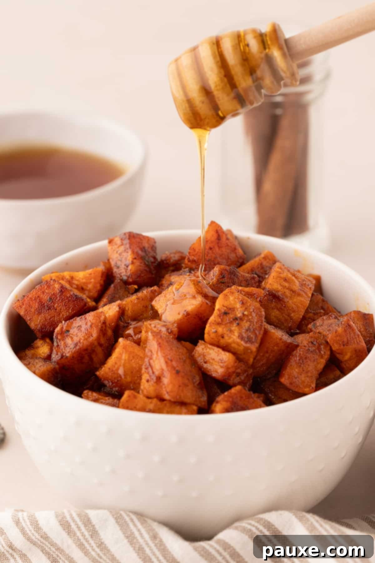 Golden Roasted Sweet Potato Bites 11 A bowl of roasted sweet potatoes with a generous drizzle of golden honey cascading over them.