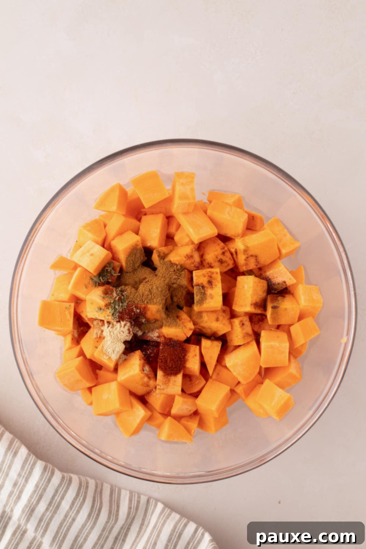 Golden Roasted Sweet Potato Bites 4 A bowl of cubed sweet potatoes with seasonings sprinkled on top, ready to be tossed.