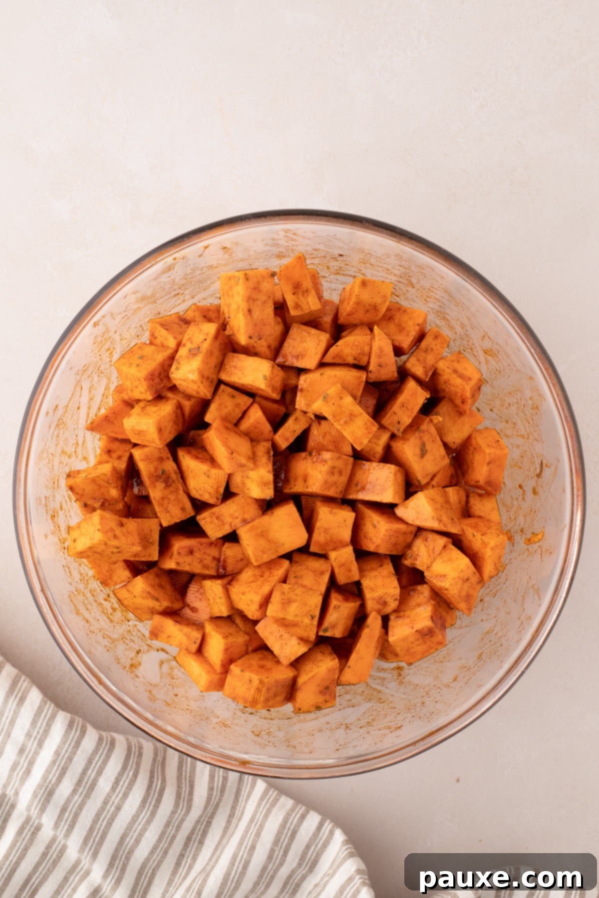 Golden Roasted Sweet Potato Bites 5 A bowl of cubed sweet potatoes perfectly tossed in seasonings and oil, showing an even coating.