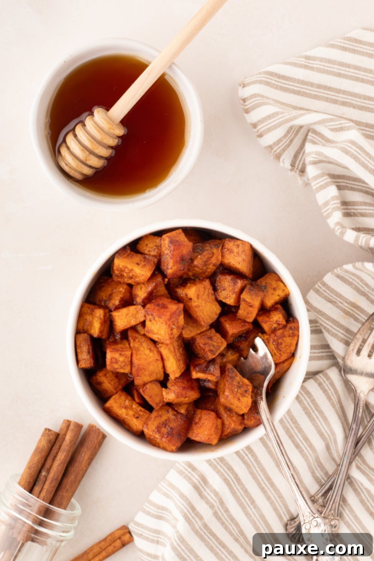 Golden Roasted Sweet Potato Bites 9 A vibrant bowl of roasted sweet potatoes, with a small decorative bowl of honey or syrup on the side, ready for drizzling.