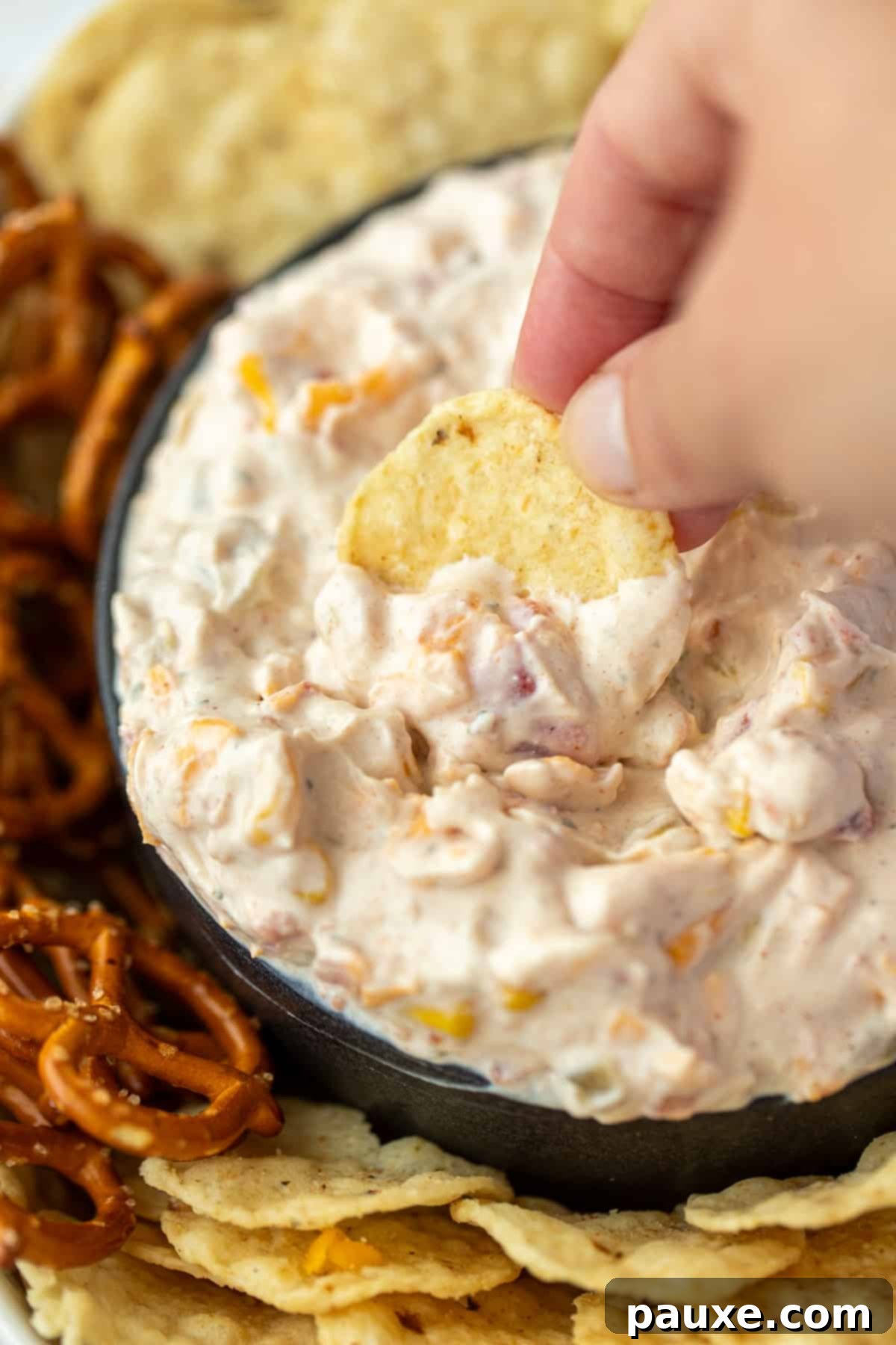 Dipping a tortilla chip into a small bowl of cheese and sour cream dip.