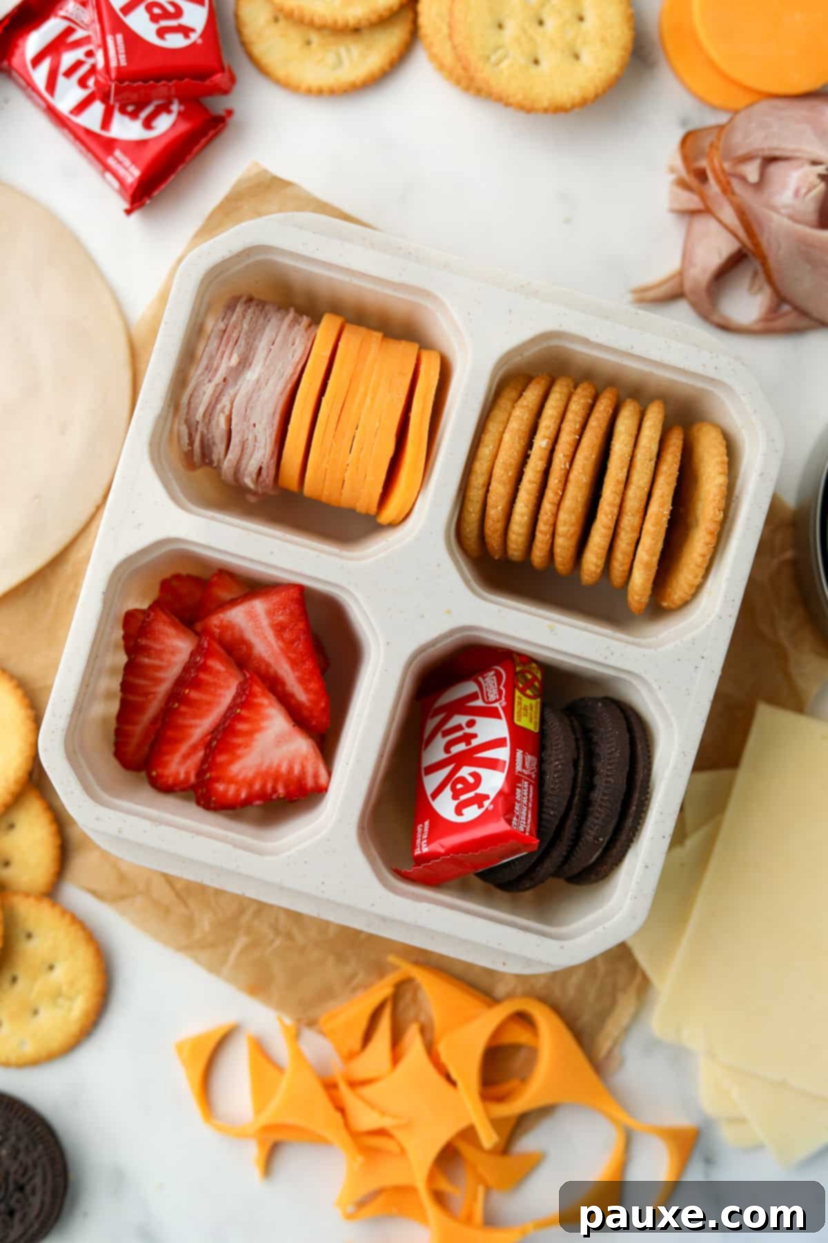 Craft-Your-Own Lunch Kits 2 A 4-compartment container filled with crackers, sliced deli meat, cheese, and sweet treats, ready for a grab-and-go lunch.