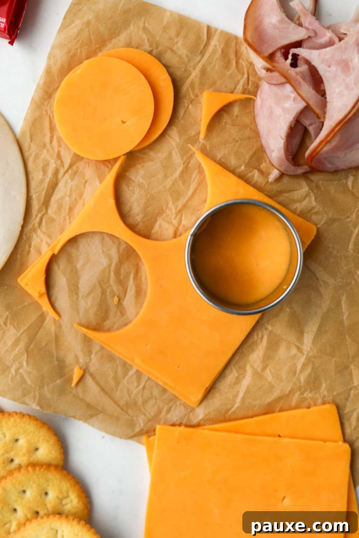 Craft-Your-Own Lunch Kits 5 A hand expertly using a circular cutter to create uniform cheese rounds from a block of sliced cheese, ideal for crafting homemade lunchables.