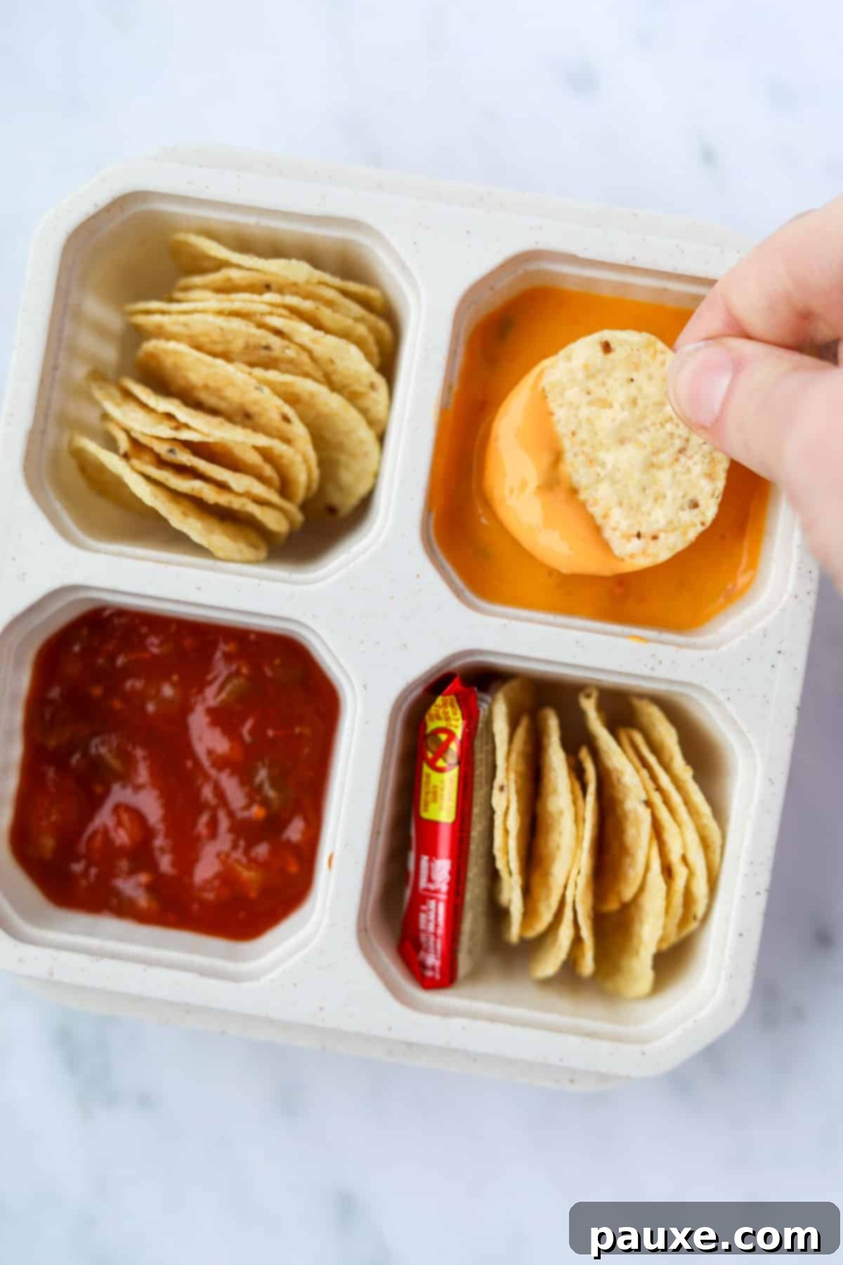 Craft-Your-Own Lunch Kits 8 A close-up shot of tortilla chips being dipped into creamy queso cheese sauce, highlighting the delicious and interactive element of homemade nacho lunchables.