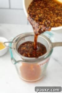 Crafting Homemade Hot Honey 14 Pouring infused honey through a fine mesh strainer.