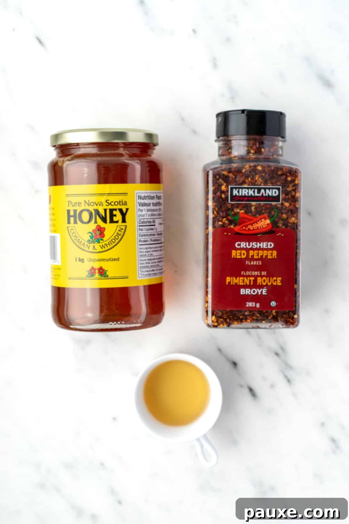 Crafting Homemade Hot Honey 3 A jar of honey, a container of crushed chiles, and a small bowl of apple cider vinegar, highlighting the simple ingredients for hot honey.