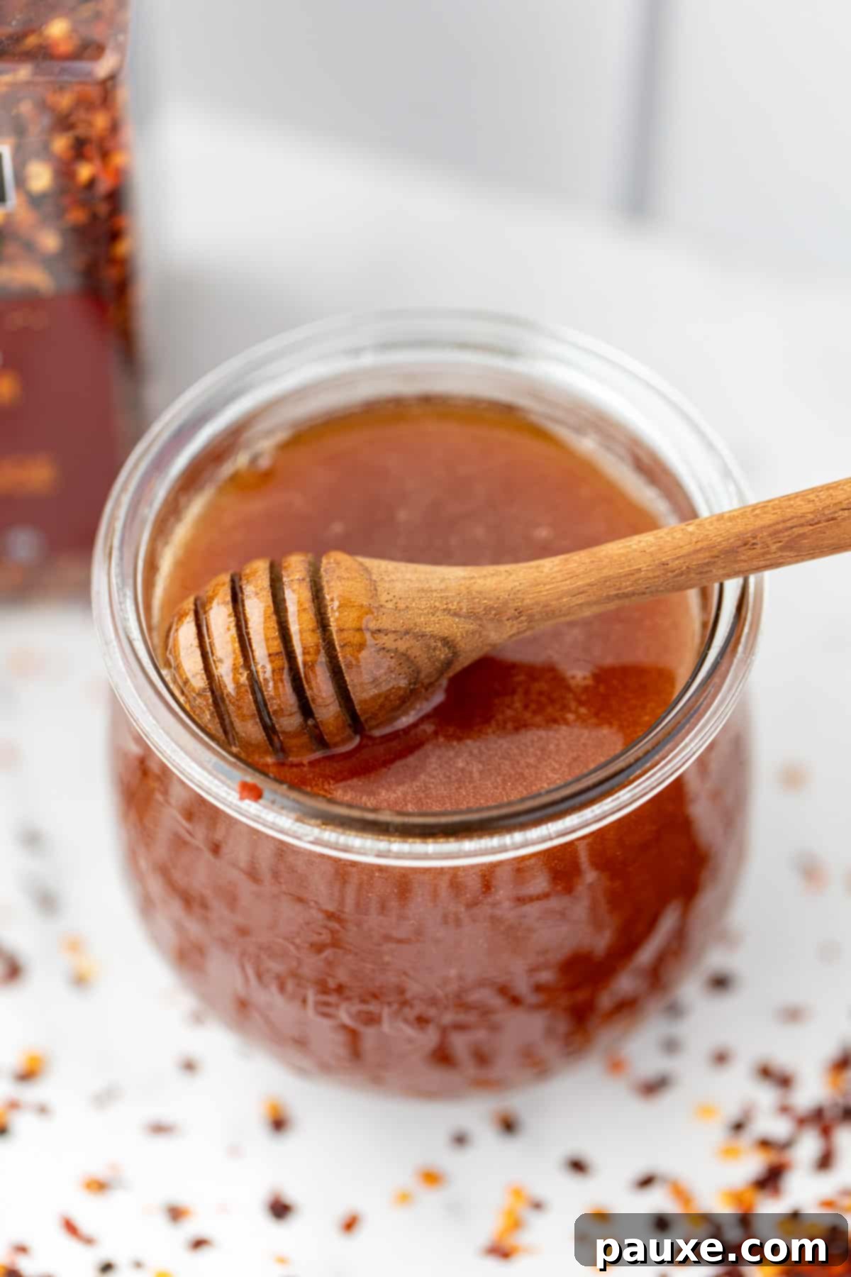 Crafting Homemade Hot Honey 9 A jar of hot honey with a honey dipper immersed in the honey, ready to serve.