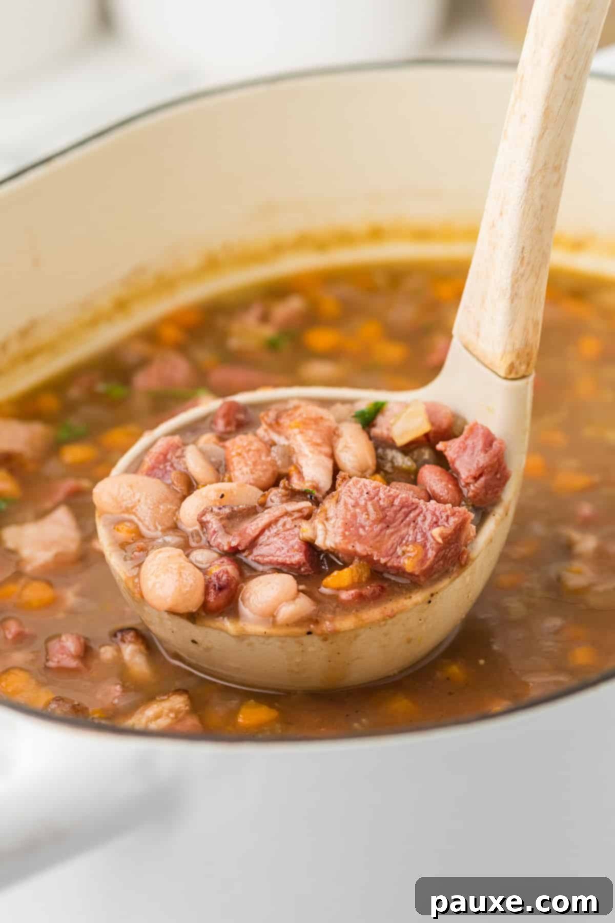 Hearty Fifteen-Bean Soup 7 A ladle filled with rich ham and bean soup, ready to be served into bowls.